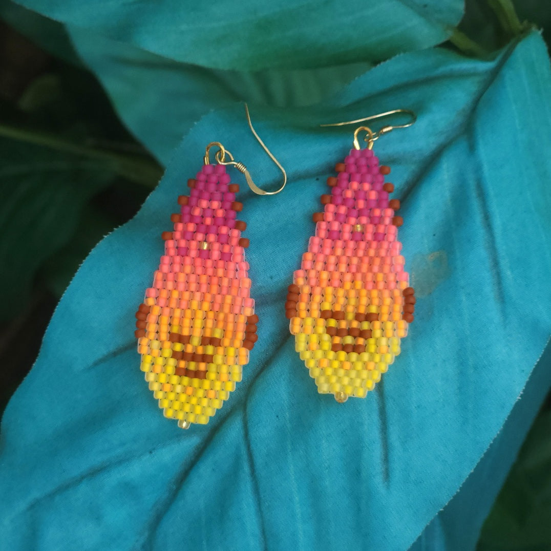 Beaded gnome-shaped earrings on a blue leaf