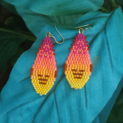 Beaded gnome-shaped earrings on a blue leaf