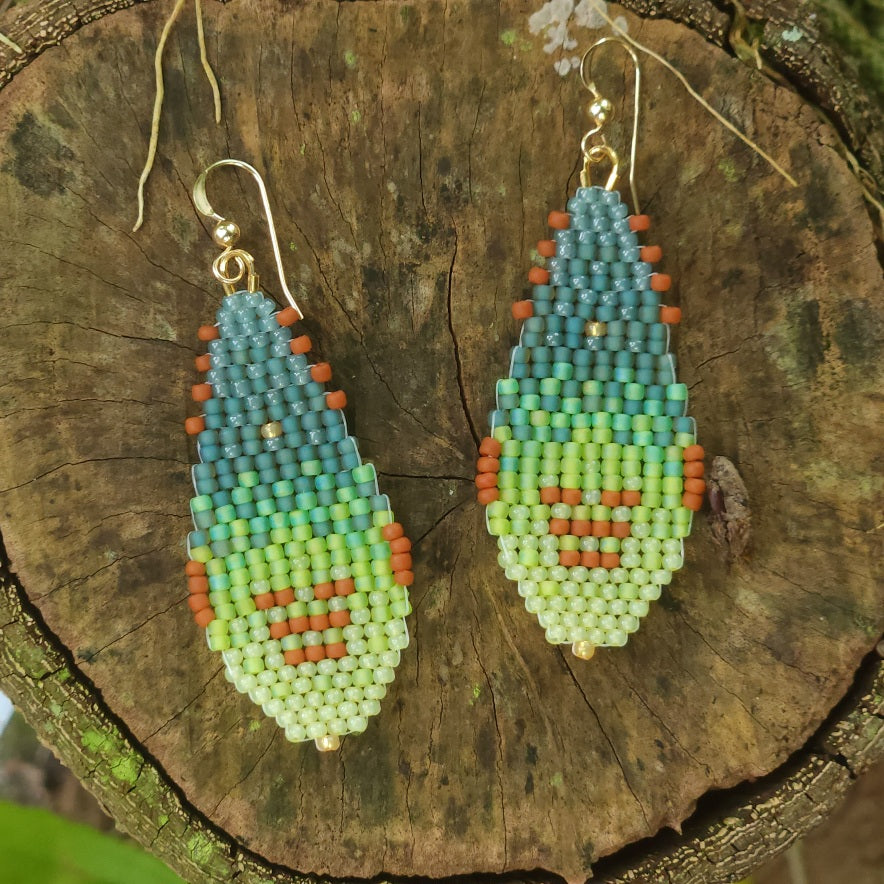 Pair of green drop beaded earrings on a wooden surface